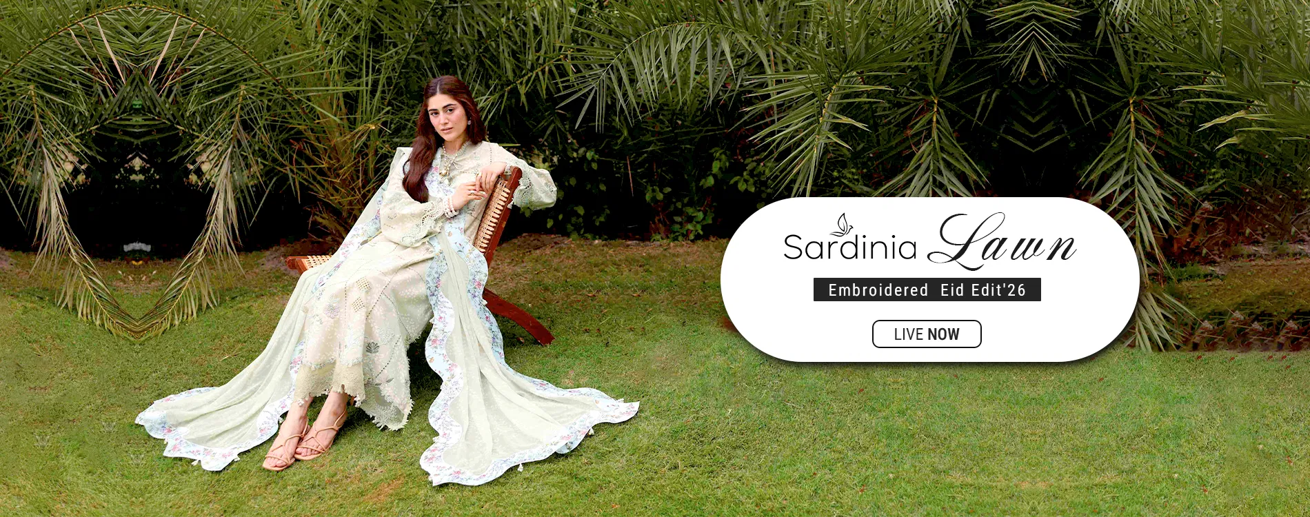 Wide homepage slider banner showcasing the launch of the Sardinia Lawn Embroidered Eid Edit '26 collection, featuring a model seated outdoors in a luxury light green unstitched embroidered luxury suit with a detailed floral lace dupatta border.