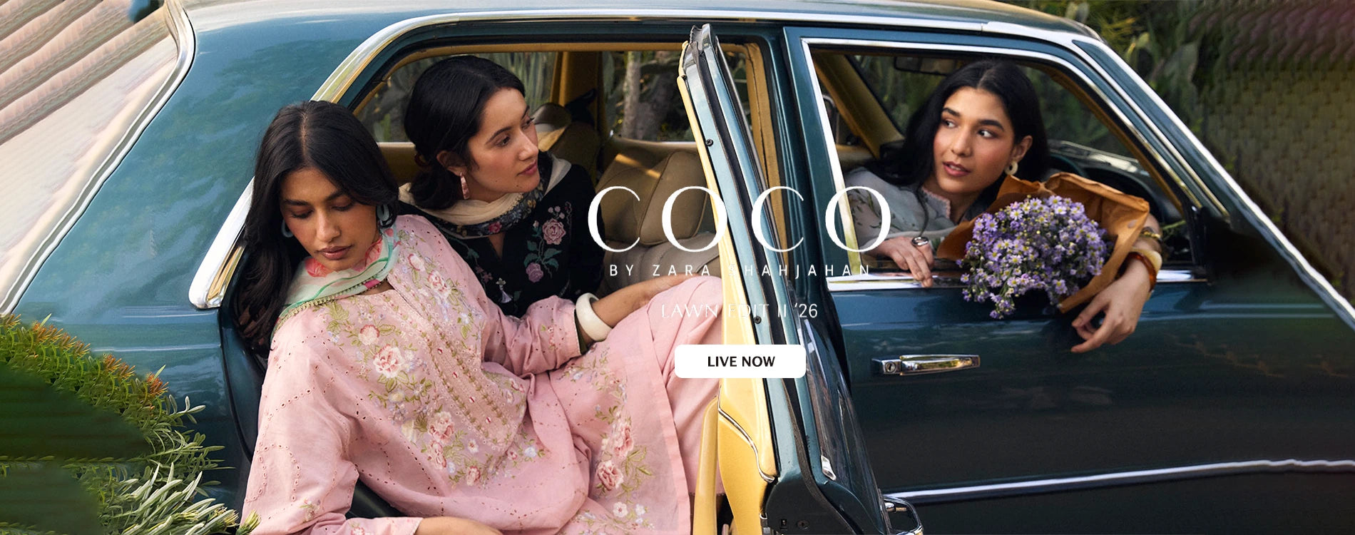 Wide homepage slider banner announcing the official launch of Coco by Zara Shahjahan Lawn Edit II 2026 collection, featuring three models posing inside a vintage teal green car wearing premium unstitched three-piece embroidered floral lawn suits.