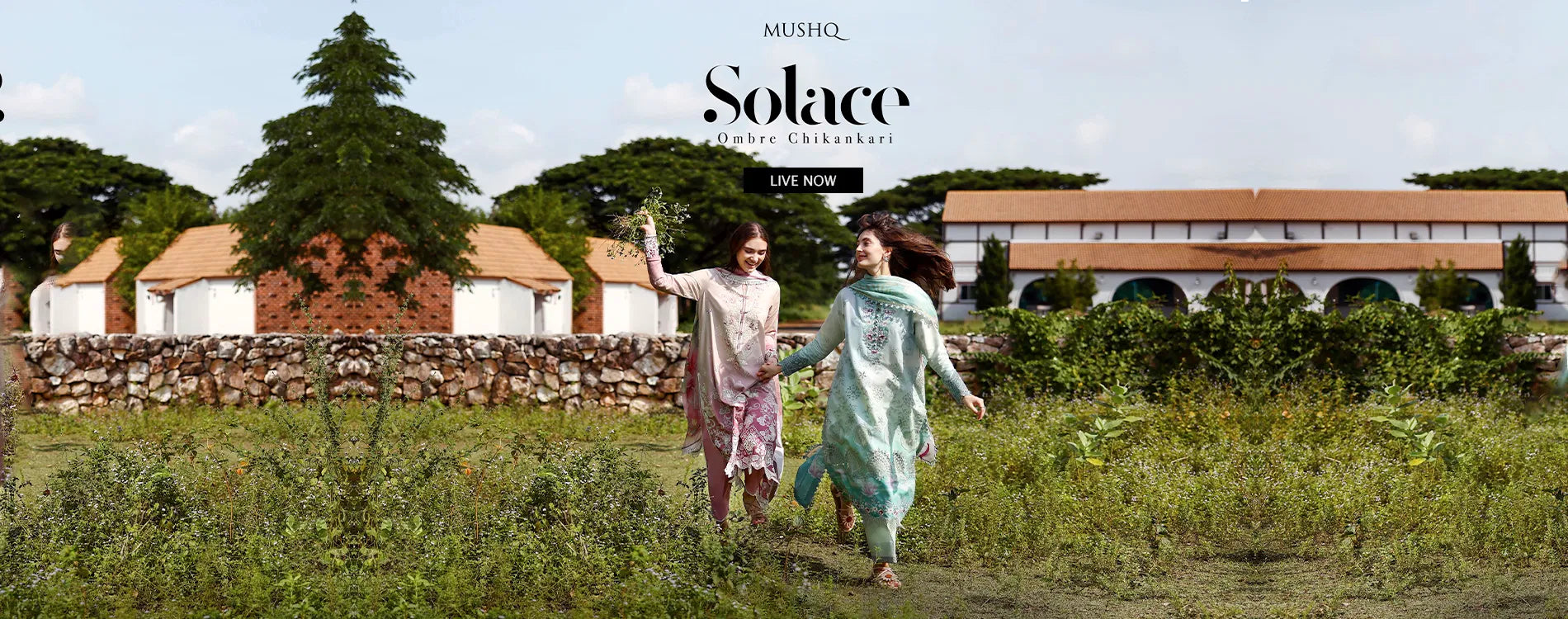 Wide homepage slider banner announcing the launch of the Mushq Solace Ombre Chikankari collection, featuring two models holding hands and running through a green field in luxury unstitched ombre dyed chikankari suits in pink and mint green hues.