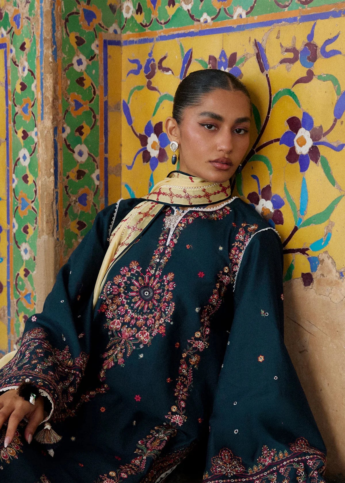 High-resolution close-up portrait focusing on the detailed multi-colored asymmetric neckline embroidery and broad sleeve cuffs.
