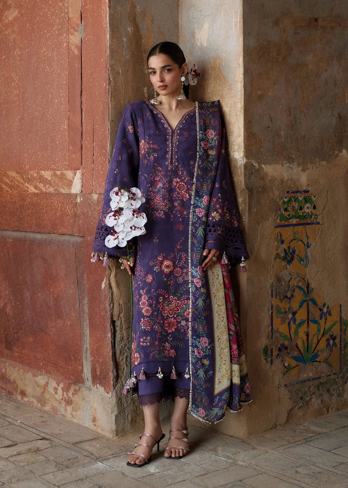 Full-length front view of ZAN Spring Summer 2026 unstitched collection design Mor in deep purple on model holding orchids.