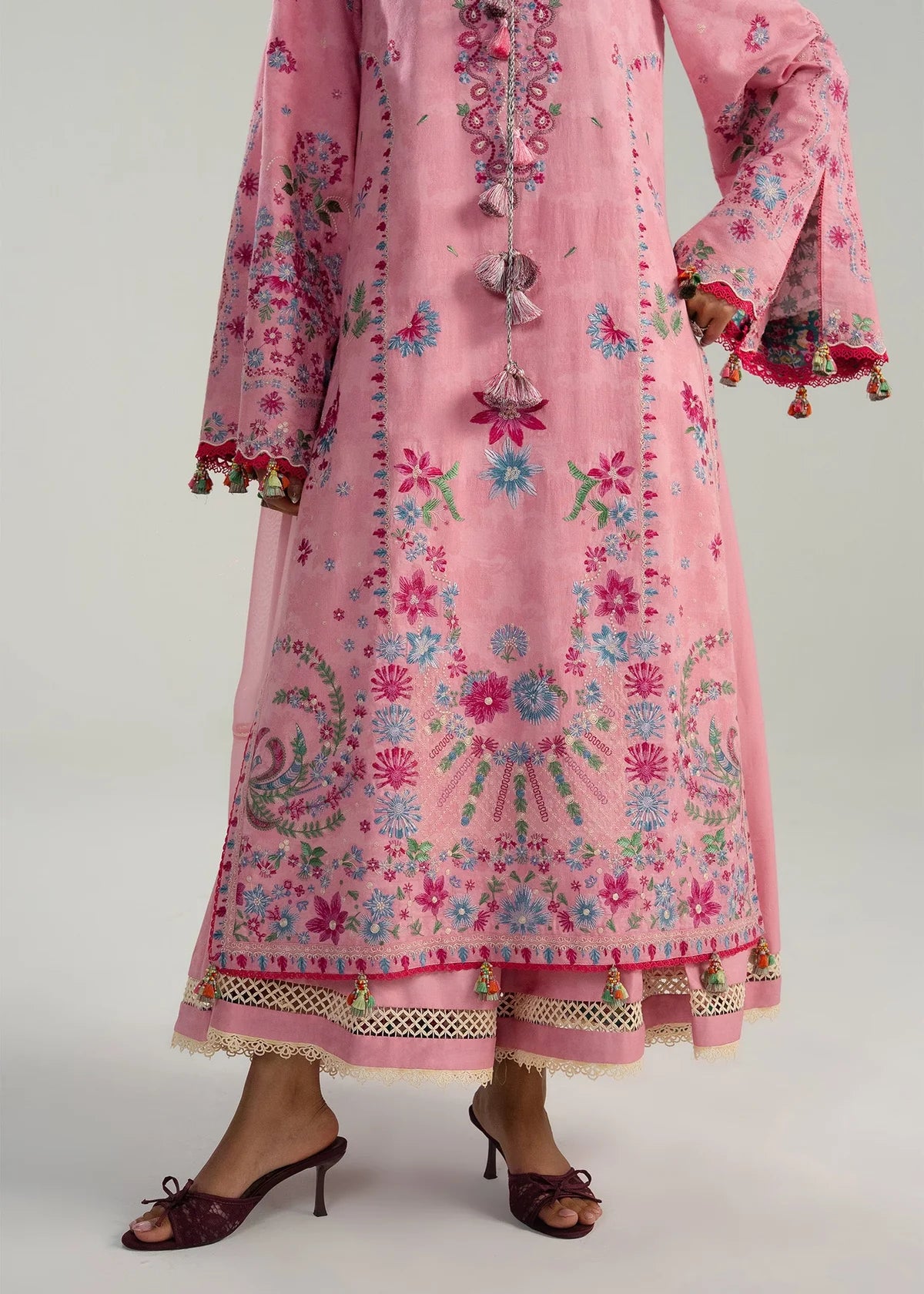 Detailed close-up view of the dense floral peacock style embroidery border patches and geometric cutout loops on the trousers.