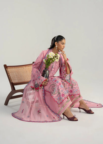 Sitting model presentation on a wicker bench highlighting the multi-panel mirror style pink and blue embroidery layout holding white daisies.