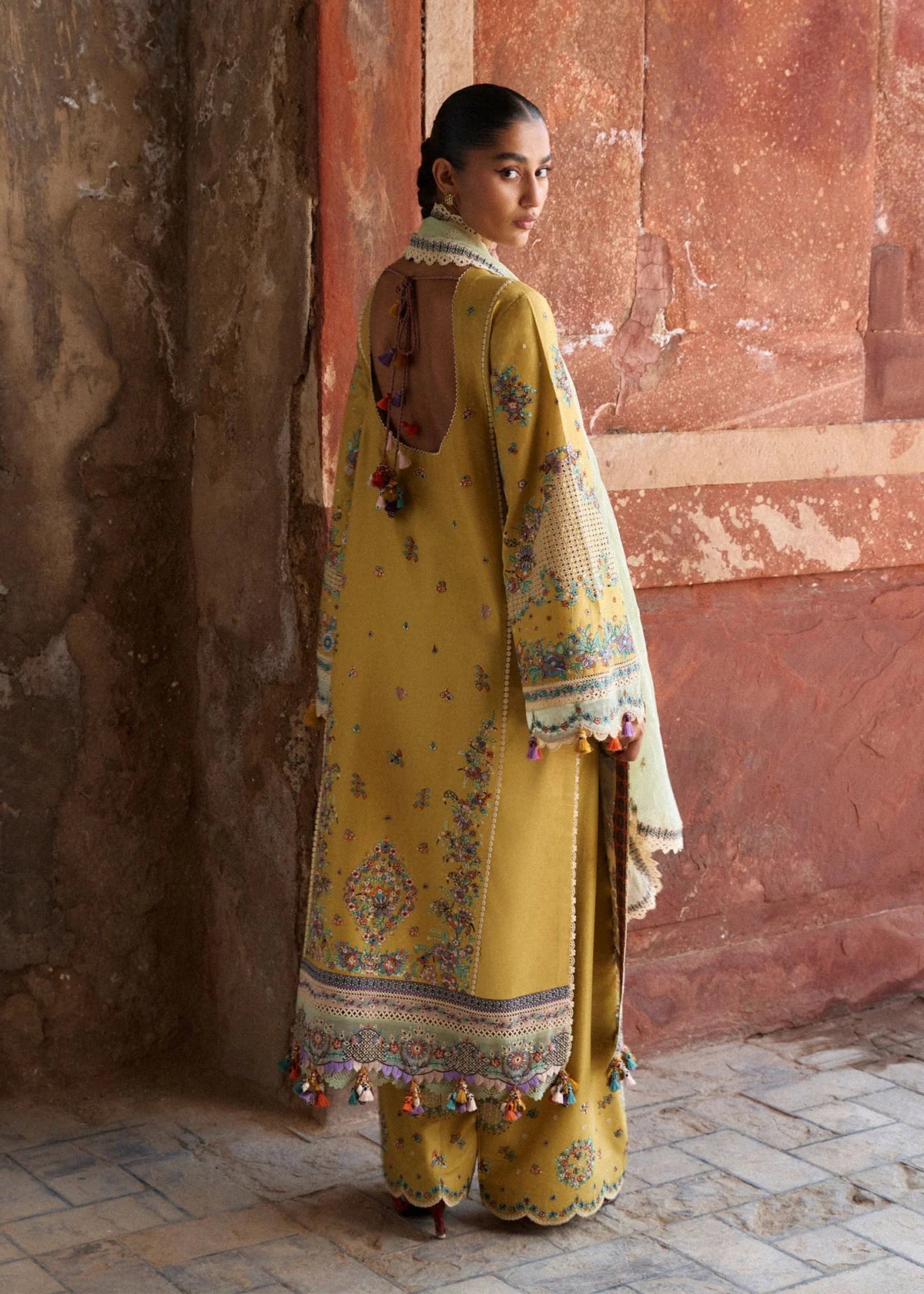 Rear model view showing the low scoop back design with tie detailing, Schiffli sleeve panels, and multi-layered hemline organza borders.
