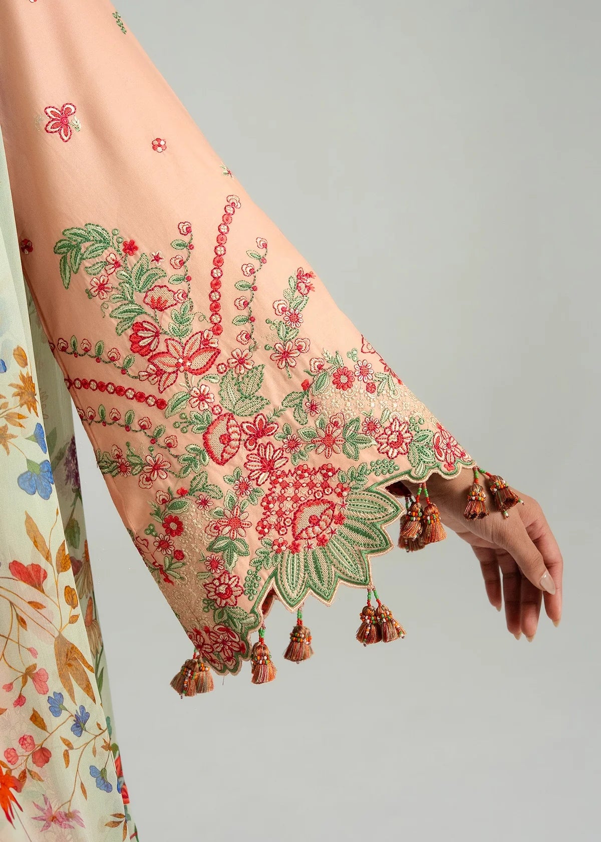 Macro view of the expansive bell sleeve cuff detailing showcasing intricate scalloped embroidery borders and hanging accents.
