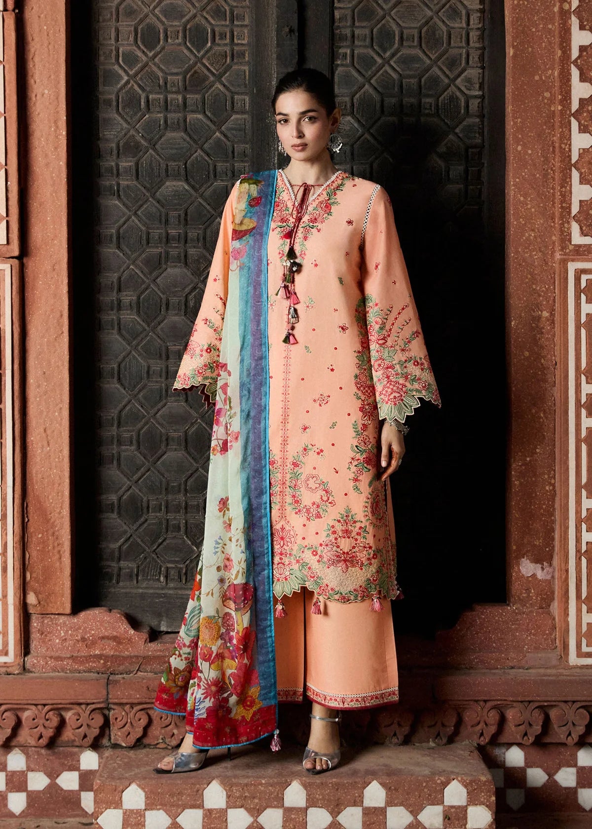 Full-length model presentation against an ancient carved wood door highlighting the straight silhouette and wide trouser matching stance.