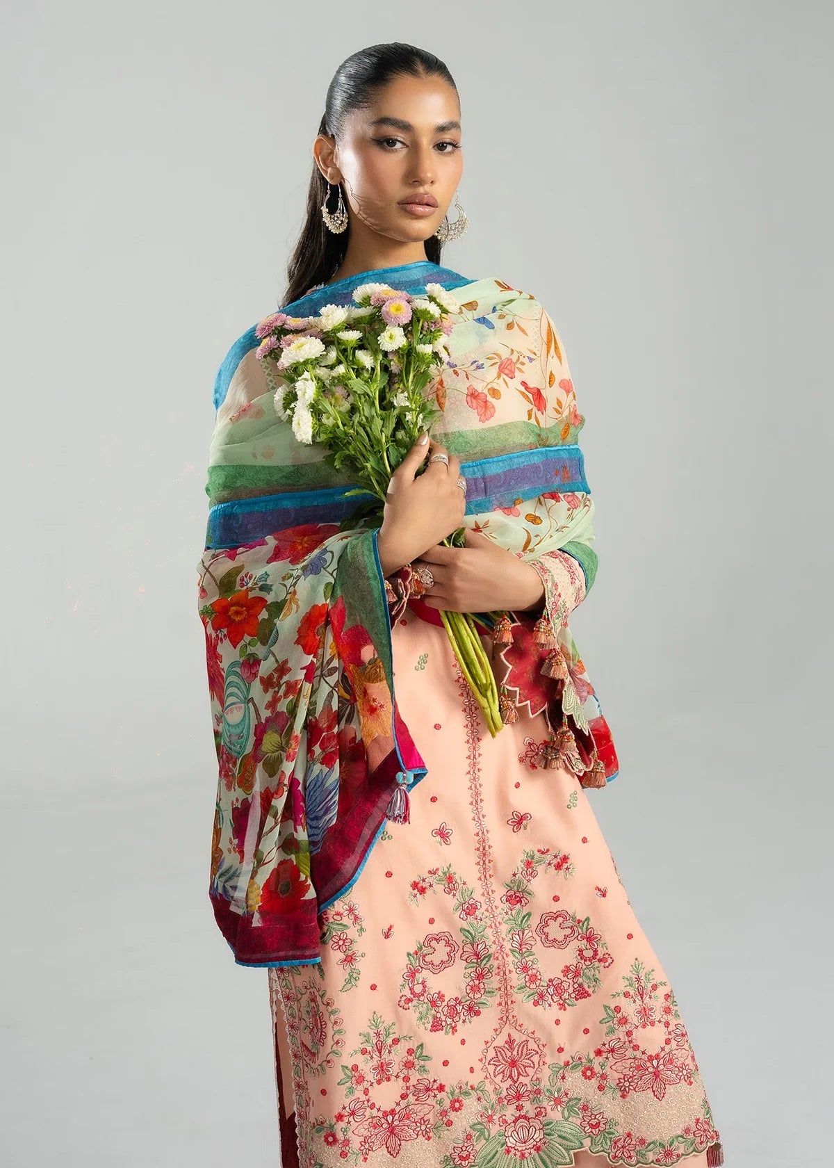 Half-length studio portrait highlighting the multi-color printed chiffon dupatta paired with the peach embroidered bodice.