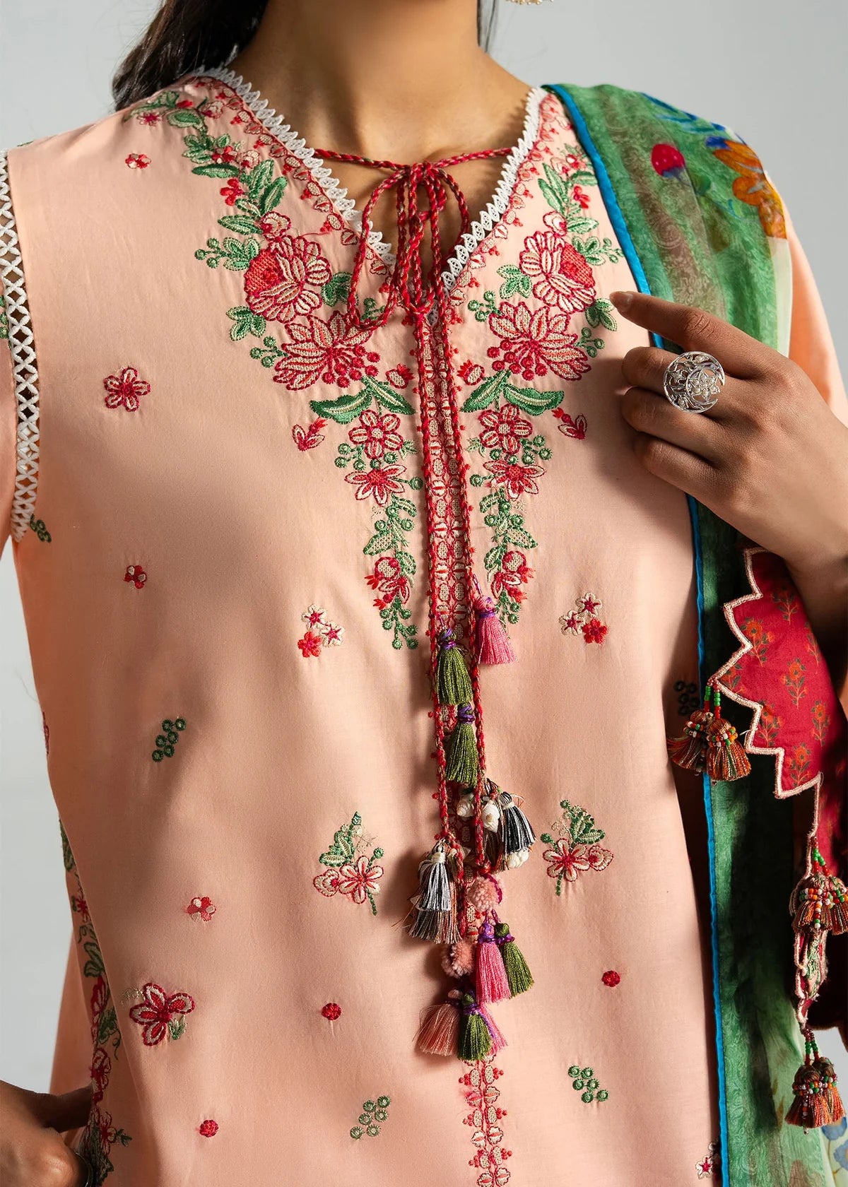 High-fidelity close-up portrait focusing on the detailed red and pink floral neckline embroidery and tasseled neck strings.